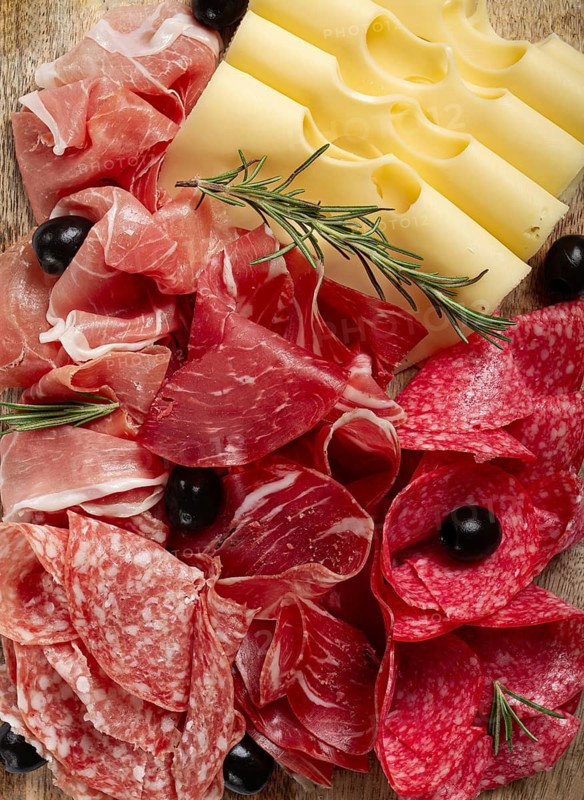 Assorted meat, appetizer, prosciutto, salami and ham, with maasdam cheese and olives, on a wooden board, breakfast, top view, close-up, no people