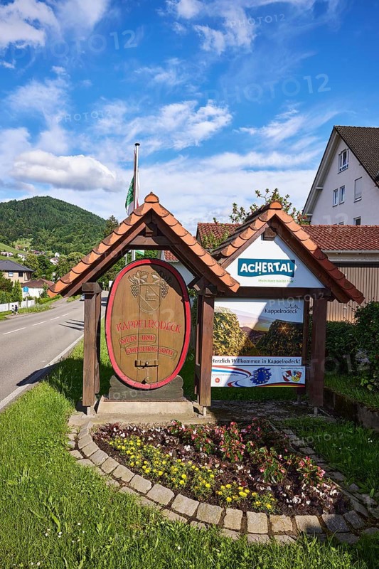 Tourist sign, wine village, holiday resort, tourist region Achertal, hilly landscape with forest, residential building, blue sky with cumulus clouds, cirrus clouds and cirrostratus clouds, main road, Kappelrodeck, Black Forest, Ortenaukreis, Baden-Württemberg, Germany