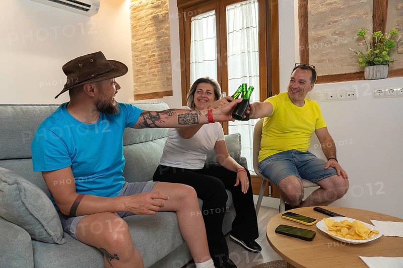 Group of friends cheering and celebrating a goal during a live sports match at home. Happy emotions, laughter, beer and togetherness indoors
