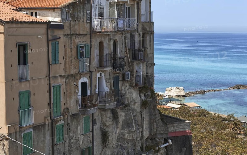 Houses in the old town centre with green shutters right by the sea, overlooking the coast, Tropea, Italy