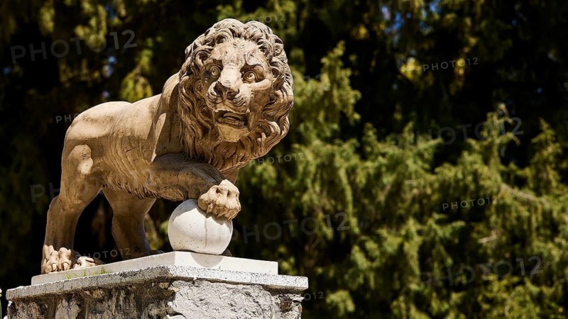 Lion statue on pedestal in front of a background of trees, Rodini Park, City Park, Rhodes Town, Rhodes, Dodecanese, Greek Islands, Greece