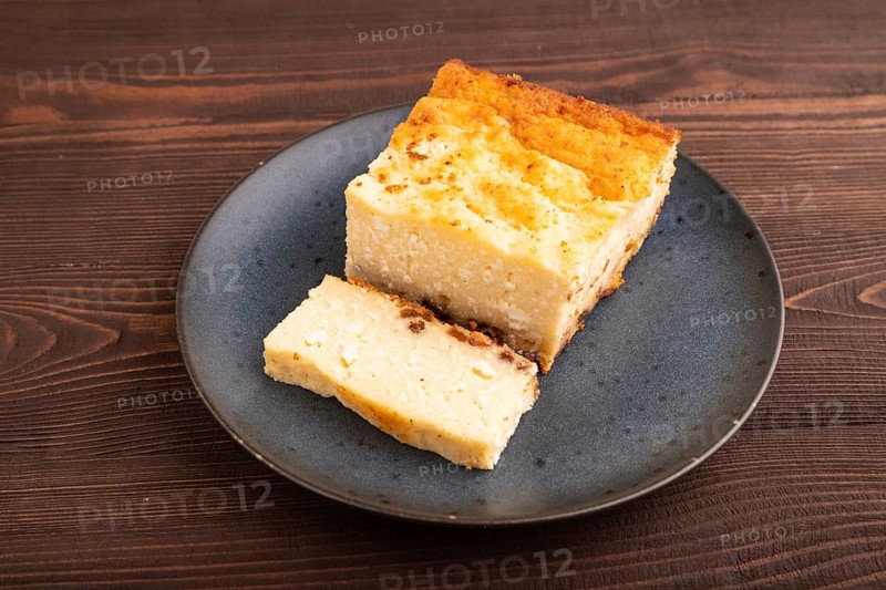 ?ottage cheese ?asserole, Curd cake, with dried apricots and raisins on brown wooden background, side view, copy space, minimalism