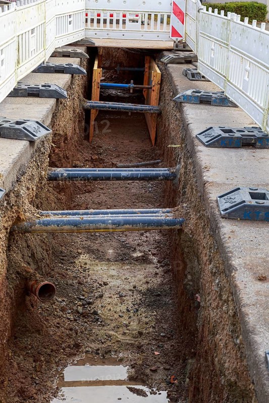 Excavation pit with safety barriers, wooden supports and earthworks along the road