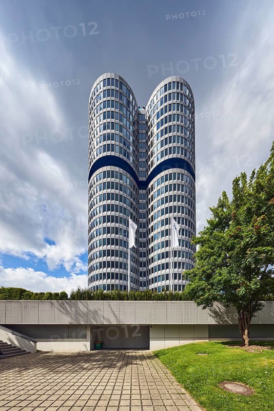 BMW group headquarters, BMW four-cylinder engine, BMW tower, BMW high-rise building, architect Karl Schwanzer, commercial building, high-rise building, modern architecture, trees, meadow, overcast sky with a little blue, dark gray cumulus clouds, Petuelring, Munich, state capital, district-free city, Bavaria, Germany