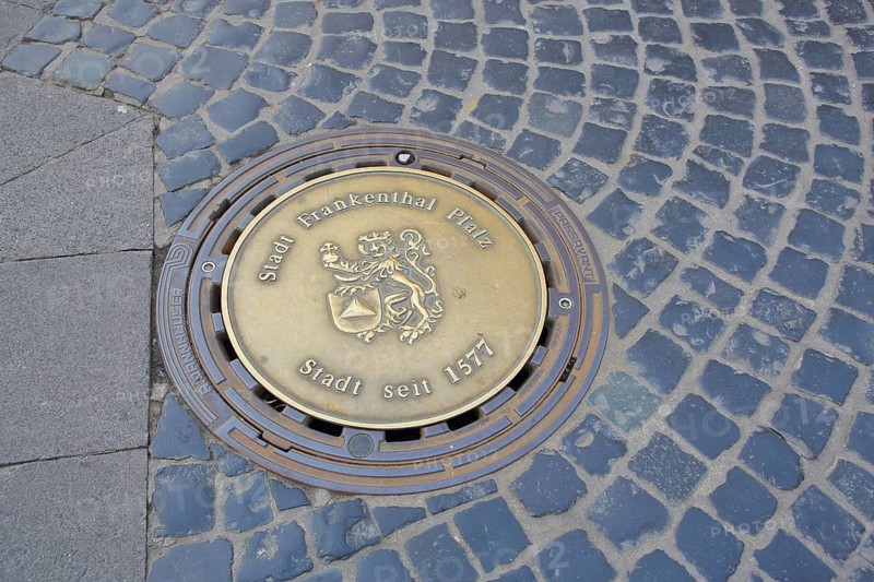 Round manhole cover with city coat of arms and date 1577 for granting city rights, inscription, casting, city history, paving stones, Frankenthal, Rhineland-Palatinate, Germany
