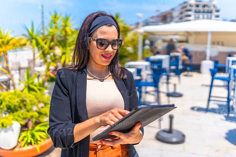 Businesswoman standing using digital tablet on a luxury terrace in summer