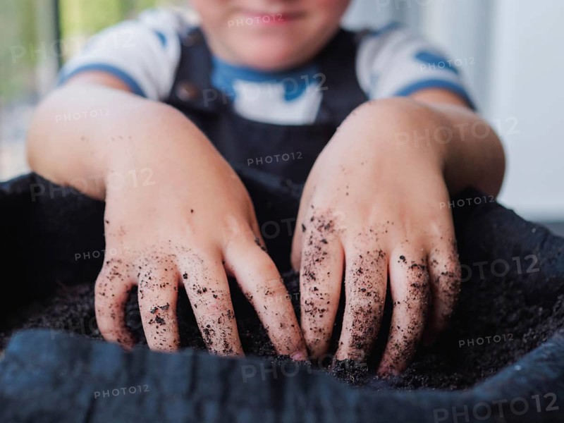 Cropped unrecognizable child busily engages in gardening, their hands covered in dirt, symbolizing a connection with nature and dedication to planting