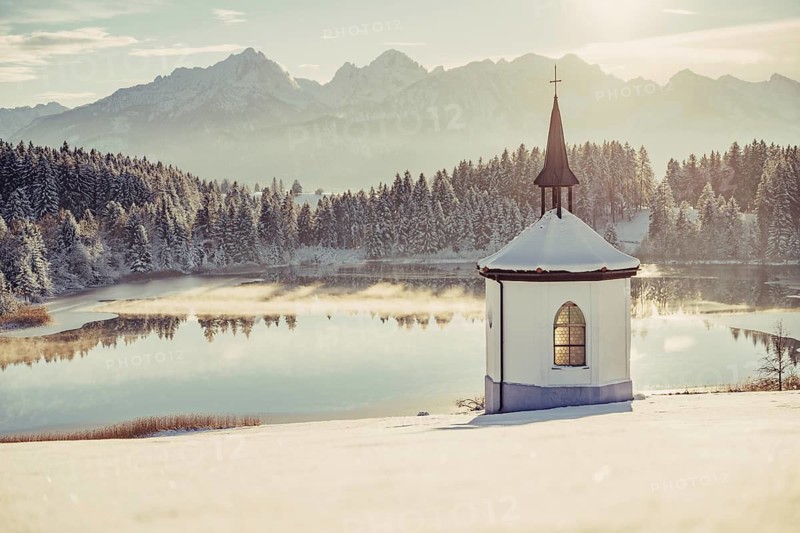 Chapel by the lake in the wintry snow-covered Allgäu near Halblech in front of an impressive mountain landscape, Bavaria, Germany