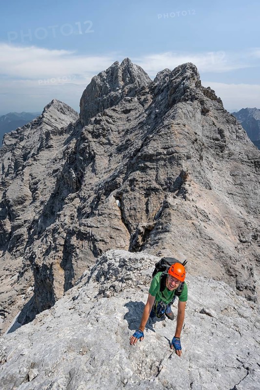 Mountaineer with helmet climbing on the rock, on a narrow rocky ridge, crossing the Jubiläumsgrat, Wetterstein range, Bavaria, Germany