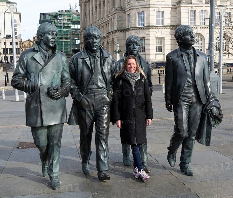 Woman standing next to The Beatles statues sculpture by Anthony Edwards, Pier Head, Liverpool, England, UK