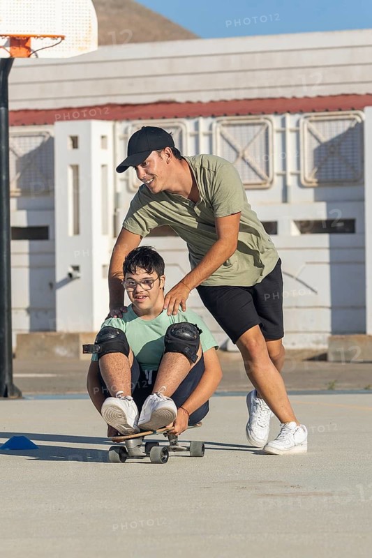 A joyful scene of a teenager with Down syndrome skating with the support of his brother The interaction highlights the importance of inclusion, promoting together the realization of sports activities