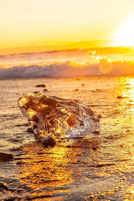 The sun rises at dawn with ice on Diamond Beach next to Jokulsarlon in winter in Iceland