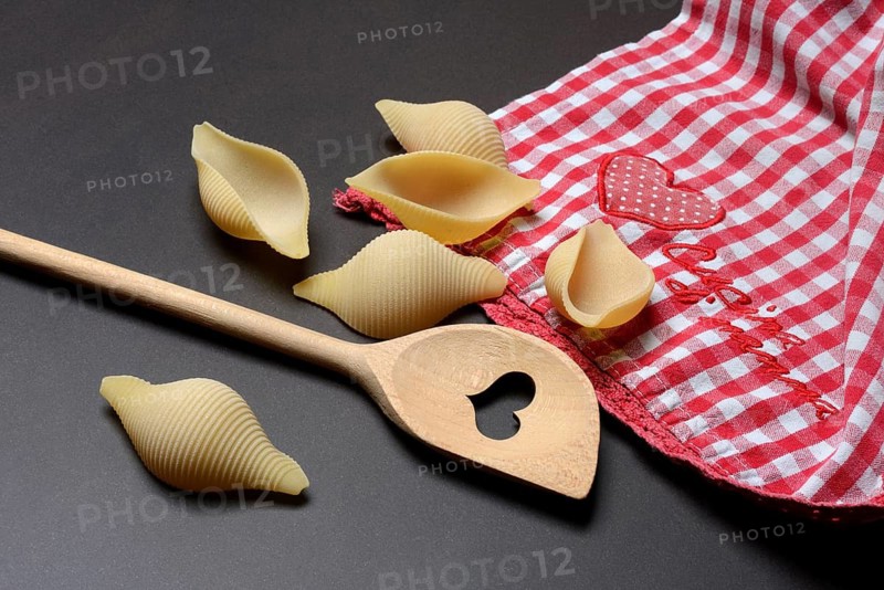 Conchiglione with wooden spoon, Italian pasta variety against a dark background, Italy