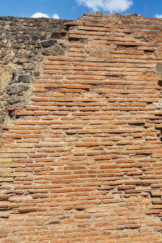 Close-up of old terracotta brick and stone wall at the ancient ruins of Pompeii, Campania region, Italy