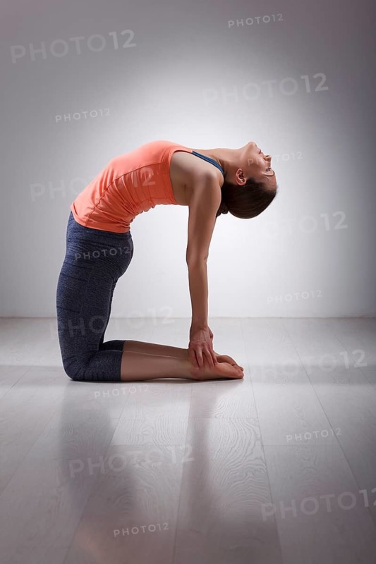 Beautiful sporty fit yogini woman practices yoga asana ustrasana, camel pose in studio