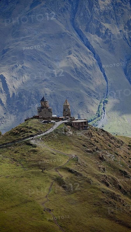 Gergeti church on a hill surrounded by mountains and gloomy atmosphere, Stepantsminda, Caucasus, Georgia