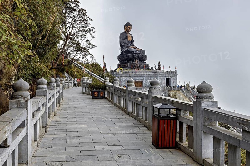 A long walkway leads to an imposing Buddha statue in a peaceful temple complex, The Buddha statues at Fansipan near Sa Pa in Vietnam