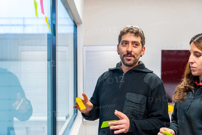 Cnc male engineer using adhesives notes during a brainstorming in the office next to colleagues