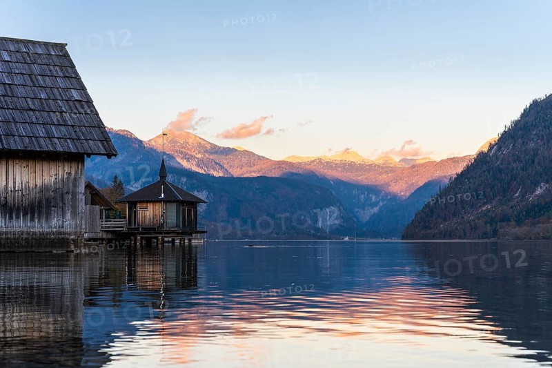 Lake Grundlsee in autumn at sunset. Boathouses on the left, mountains in the background. Blue sky, good weather. Grundlsee, Styria and Styrian Salzkammergut, Upper Austria, Austria