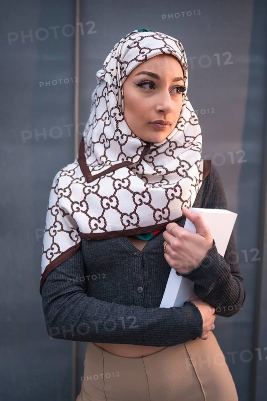 Portrait of an Arab girl with a white veil at the computer on the terrace of a coffe shop