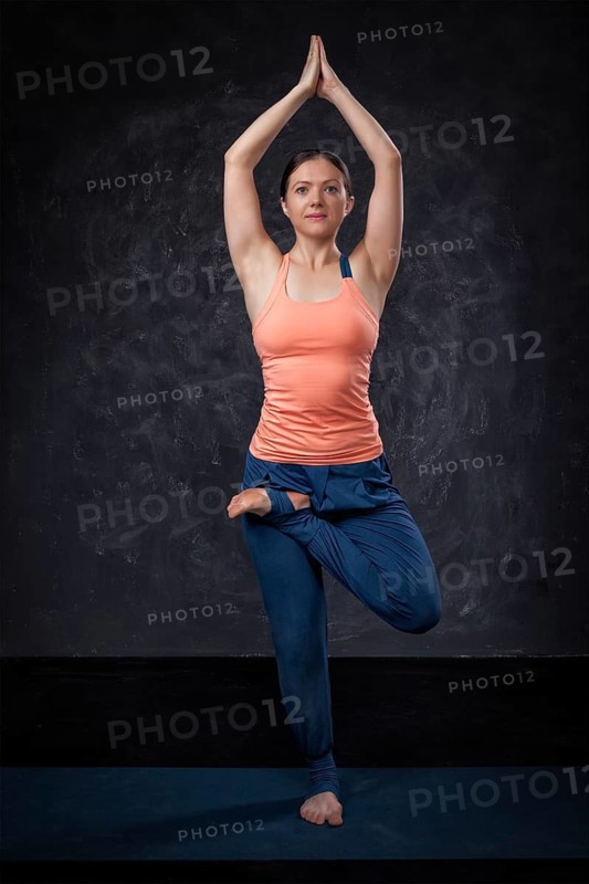 Beautiful sporty fit yogini woman practices yoga asana Vrikshasana, tree pose