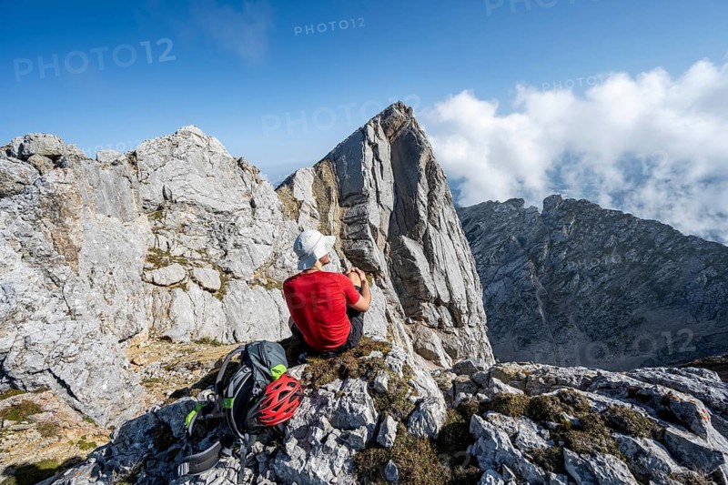 Mountaineer sitting on a rock and enjoying the view, mountain tour to the summit of the Hochkalter, Hochkalter crossing, Berchtesgaden Alps, Bavaria, Germany