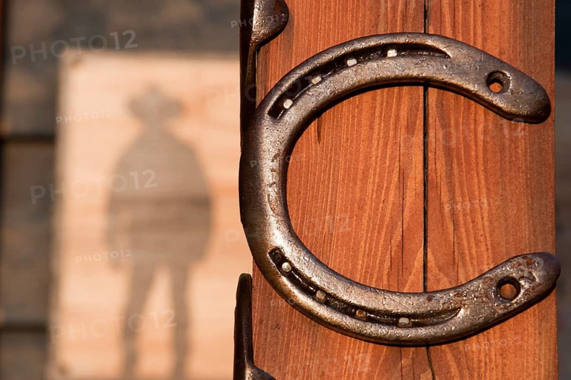 Horseshoes nailed to a pole behind an advertising sign, like for a cowboy saloon in the Wild West in sunset light in Wroclaw, Poland
