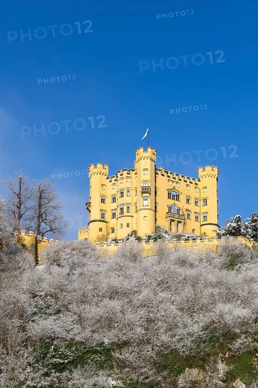 A yellow castle with eye-catching towers on a snow-covered hill under a blue sky, Hohenschwangau Castle, Schwangau, Königswinkel, Ostallgäu, Allgäu, Swabia, Bavaria, Germany