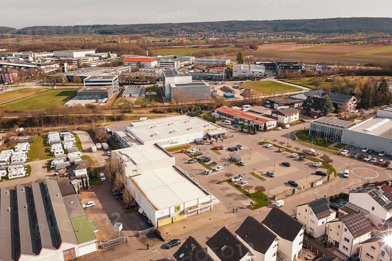 Industrial area with shopping center and fields in the background, under clear sky, Gärtringen, Böblingen district, Germany