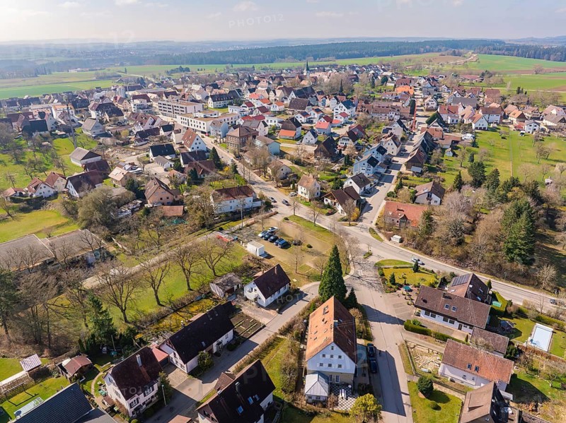 Densely built-up village with various buildings and neighbouring green areas shown in perspective from the air, Nagold Hochdorf, district of Calw, Germany