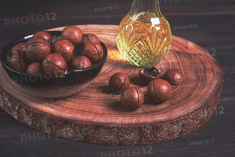 Bottle of macadamia oil, on a wooden board, with macadamia nuts, wooden background, selective focus, no people