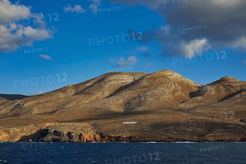 View of a hilly coastal landscape with clear sky and scattered clouds, Kassos Island, neighbouring island of Karpathos, Dodecanese, Greek Islands, Greece