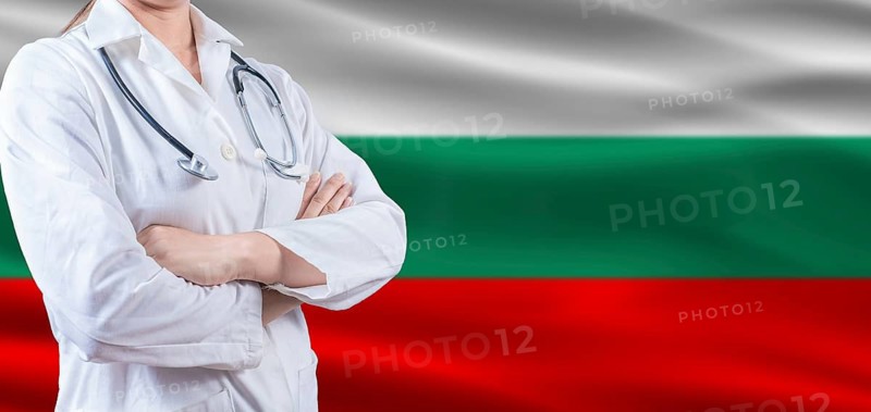 Doctor With Crossed Arms On Bulgarian Flag. Bulgaria Health And Care Concept. Female Doctor On Bulgarian Flag