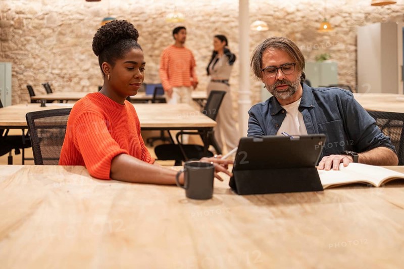 A diverse group of professionals collaborates at a modern coworking space They focus on shared tasks, promoting creativity and teamwork in a dynamic office setting