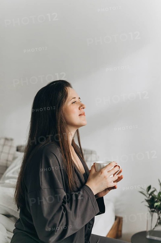 A woman enjoys a quiet moment with a cup of tea, reflecting on wellness and healthy living. This image encapsulates peace, mindfulness, and a balanced lifestyle