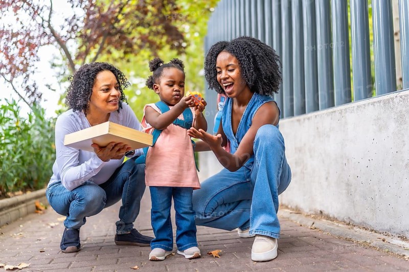 Three generations of african women at the school building entrance picking up a girl