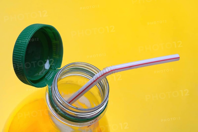 Orange juice in plastic bottle with cap and straw