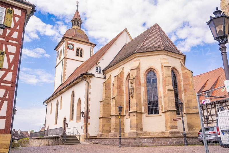 Historic church with bell tower in front of a blue sky with white clouds, Knittlingen, Germany