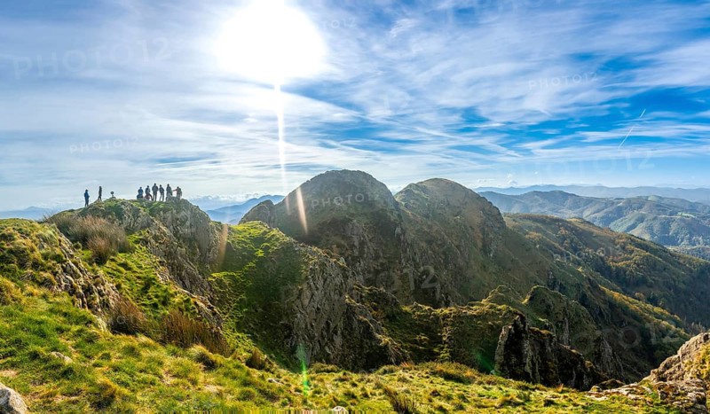 Group of hikers standing on the peak of aiako harria mountain enjoying the stunning view of the basque country landscape