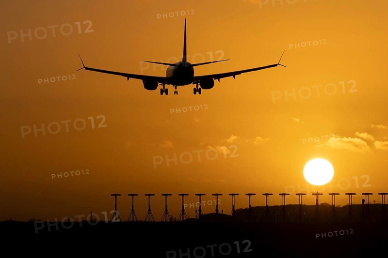 Boeing 737 commercial passenger airliner jet aircraft of Ryanair airways in flight on approach to land over runway lights at sunset at London Stansted airport, Essex, England, United Kingdom