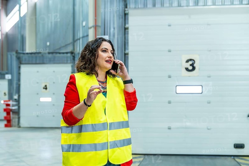 Woman talking to the mobile phone while working in a distribution warehouse