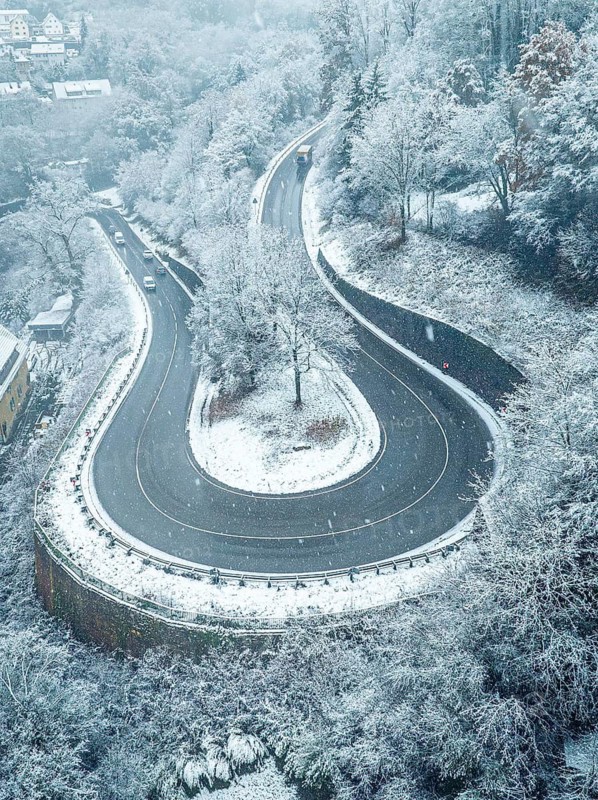 Snow-covered winding road surrounded by trees from a bird's eye view, Black Forest, Calw, Germany
