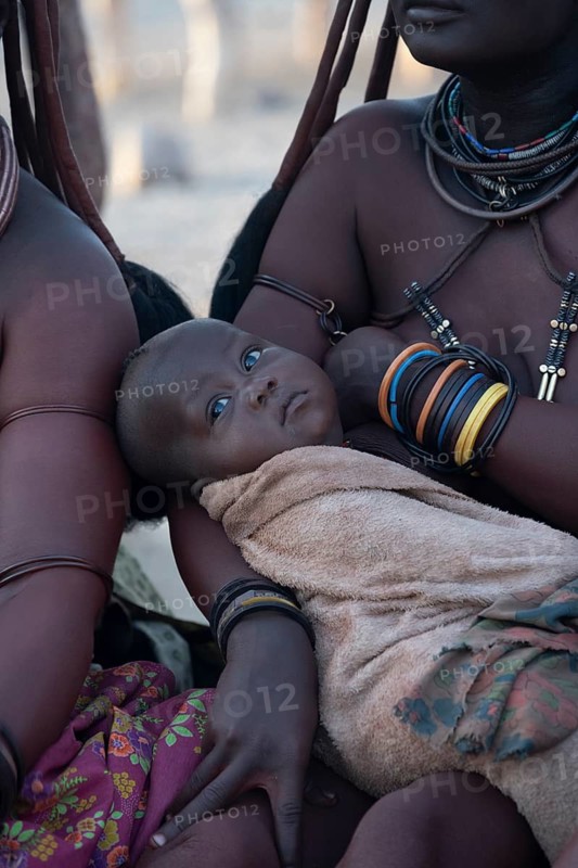 Baby in the arms of a Himba woman, traditional Himba village, Kaokoveld, Kunene, Namibia