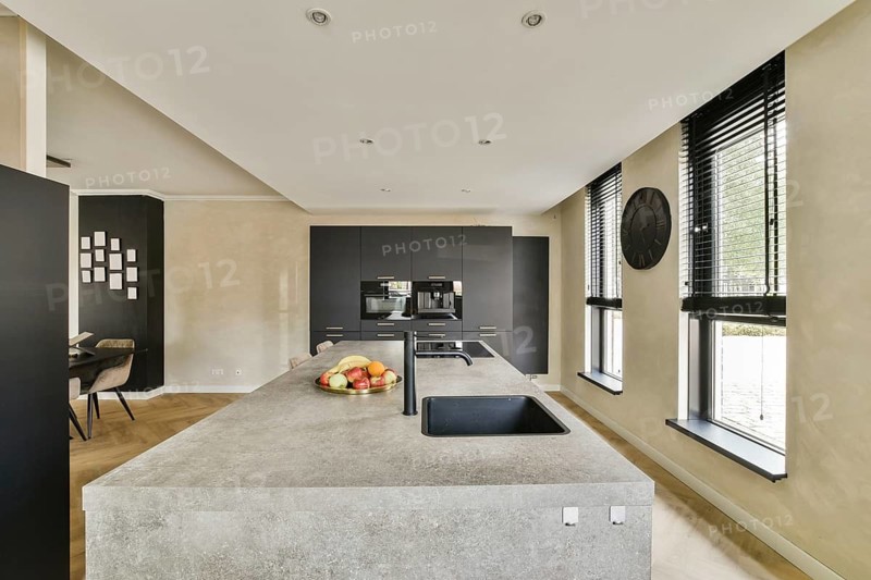 A sleek and contemporary kitchen featuring an island, modern appliances, and a minimalist design with natural lighting and wooden floors