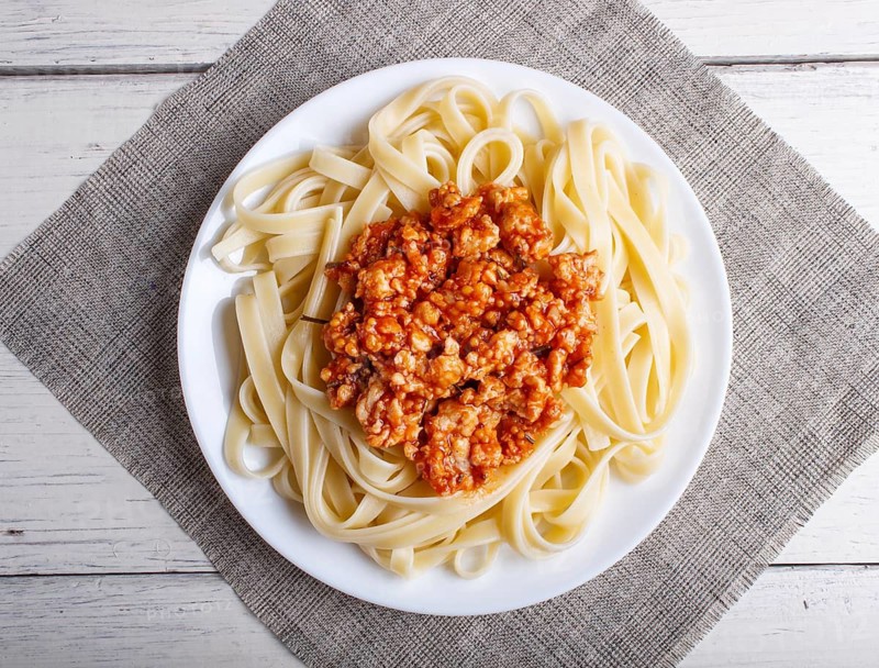 Fettuccine bolognese pasta with minced meat on white wooden background. top view, close up