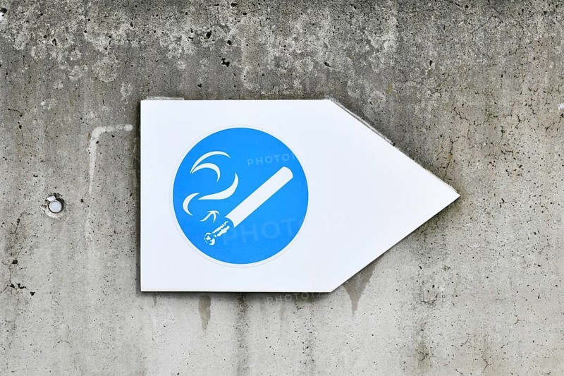 Germany, May 2025: White and blue arrow shaped sign with cigarette pointing towards designated smoking area