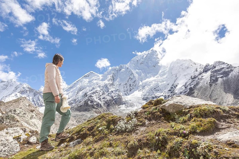 A woman in hiking gear embarks on an adventurous trek in the Himalayas, with the majestic Everest summit in view. The scene captures the thrill of exploration and nature's beauty