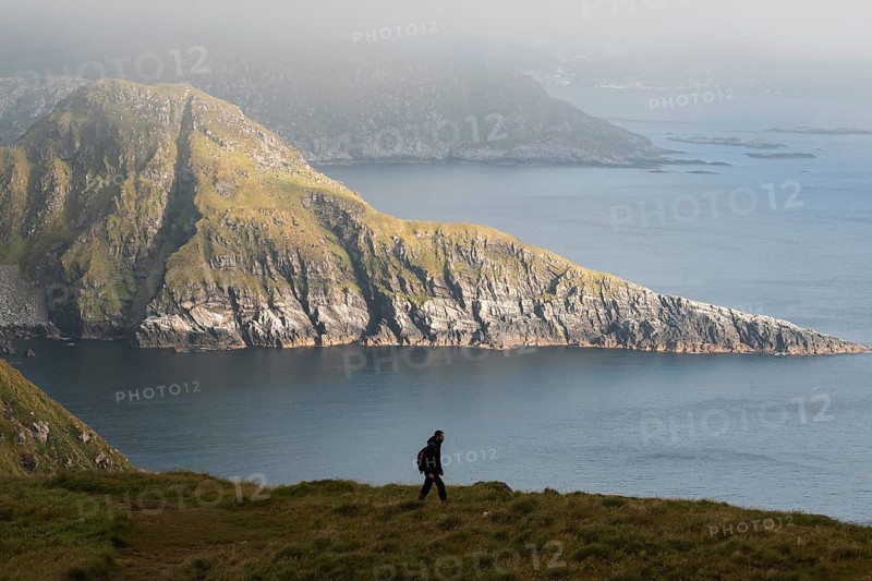 A hiker explores the stunning coastal mountains of Norway, emphasizing adventure and tranquility The breathtaking landscape captures the spirit of outdoor exploration