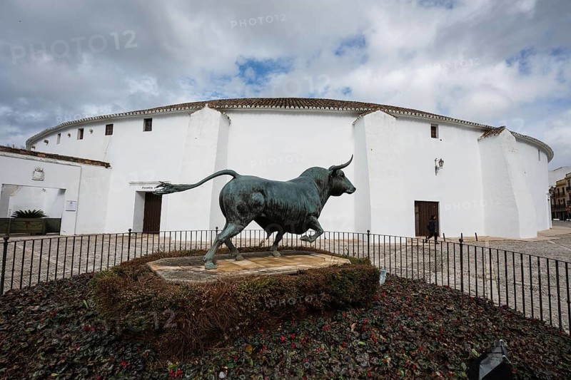 The white exterior of the Plaza de Toros de Ronda with a bronze bull statue in the foreground, celebrating Spanish bullfighting tradition in Ronda, Spain