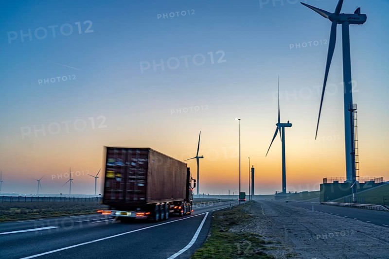 Lorry on the road from Euromax Terminal Rotterdam, ENECO wind farm on the dike around the port of Maasvlakte 2, 22 wind turbines with a capacity of 116 megawatts, sunset, Rotterdam, Netherlands